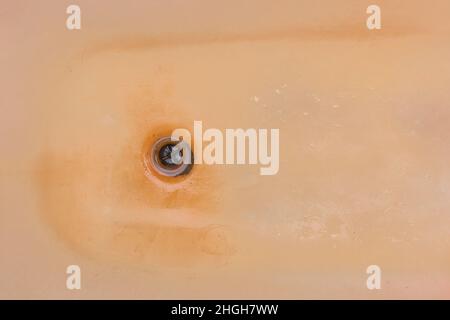 Old dirty bath with rust and a hole for drain fluzing impure water into sewer. Stock Photo