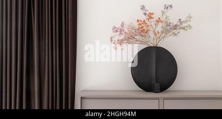 Dried colourful spring flowers in black hand glazed ceramic vase in nordic style against white wall. Minimal interior decoration concept Stock Photo