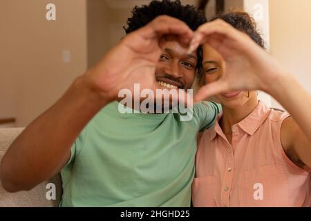 Biracial couple making heart shape with hands gesturing love at valentine's day Stock Photo