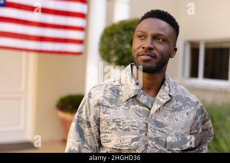 Thoughtful african american army man looking away against house with america flag Stock Photo