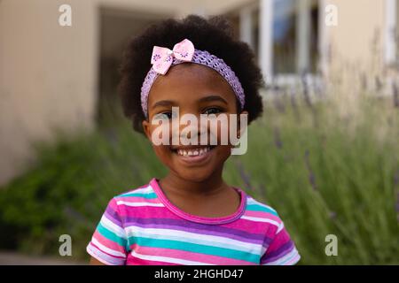 Portrait of smiling cute african american girl wearing headband and striped t-shirt