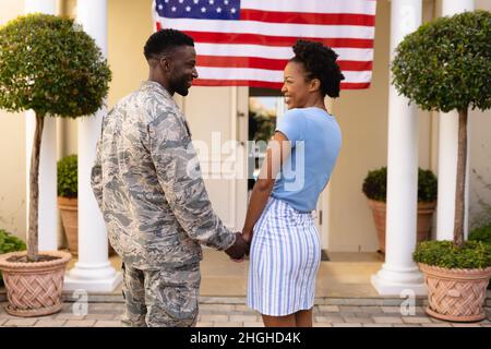 Smiling military man holding hands of african american woman while looking at each other Stock Photo