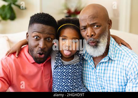 Portrait of african american grandfather, father and granddaughter making silly faces at home Stock Photo