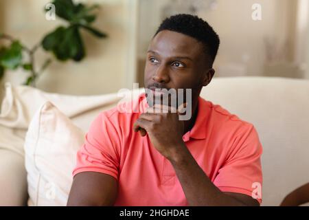 Thoughtful african american young man sitting on the couch at home Stock Photo