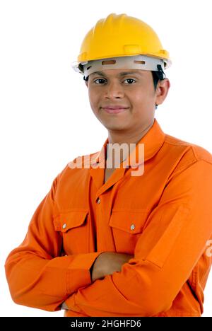 Mumbai; Maharashtra; India- Asia; Dec. 26; 2009 - Happy indian handsome young man worker wearing uniform and helmet, crossed hands white background. Stock Photo