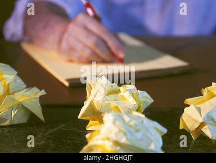 Paper balls or paper ball, trash. Man writing list on legal pad and discarding ideas. Close up of entrepreneur  working at desk dissatisfied Stock Photo