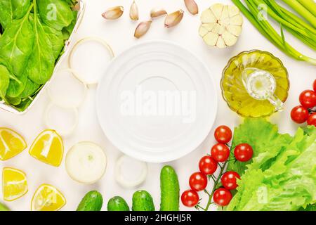 Organic farm vegetables and empty white plate on a white background. The concept of vegan healthy food and detox. Ingredients for vegetables salad Stock Photo