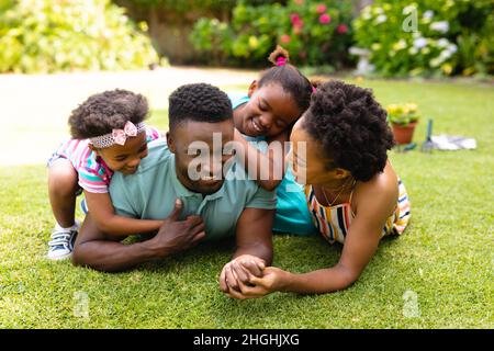 Happy african american family lying on grass at backyard garden Stock Photo