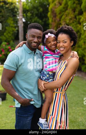 Portrait of smiling african american parents carrying daughter at garden Stock Photo