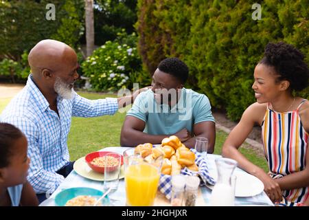 Cheerful african american family enjoying brunch at dining table in backyard Stock Photo