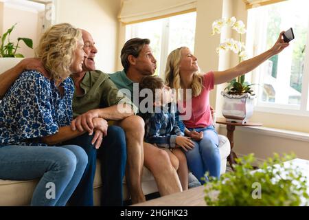 Caucasian three generation family taking a selfie while sitting on the couch at home Stock Photo