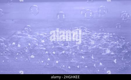 Rainbow soap bubbles on a white wooden table. Relaxation and imagination concept, childhood. Very Peri toned image. copy space. Stock Photo
