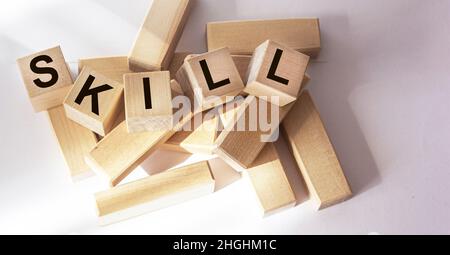 A wooden cube with the word SKILL on a white table. Stock Photo