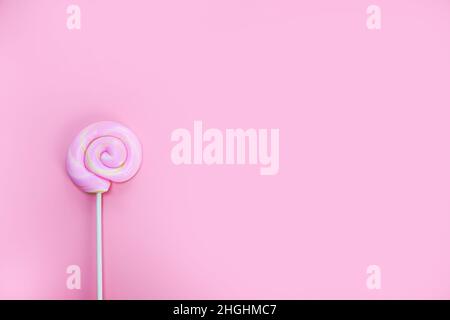 Colorful spiral lollipop on pink background top view, hard candy, sugar sweets concept copy space Stock Photo