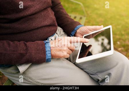 Information at your fingertips. Closeup shot of a man using a digital tablet in the park. Stock Photo