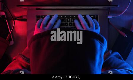 hacker working on laptop at night . hands of a hacker in rubber gloves Stock Photo