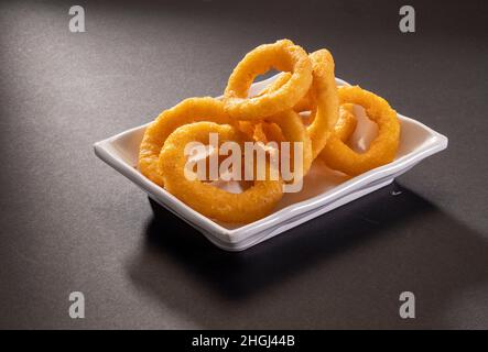 Fried onion rings served in white tray isolated on dark grey background top view Stock Photo