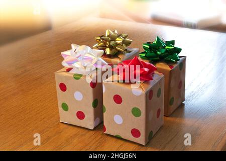 Four beautifully wrapped gift boxes on wood table with colorful bows. Stock Photo