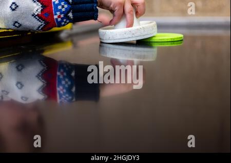 Selective focus on a small child trapping the puck of an air hockey table with the paddle.  Stock Photo