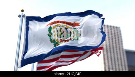 the flag of the US state of West Virginia waving in the wind with the American flag blurred in the background. Stock Photo