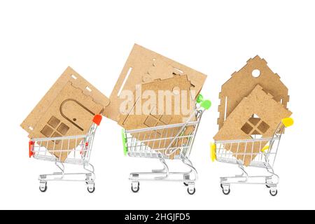 Elements of a miniature house model kit in three small shopping carts isolated on white. Renovation and house construction concept. Stock Photo