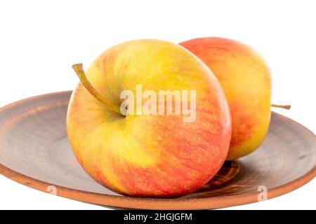Three red juicy apples on a clay plate, macro, isolated on white. Stock Photo