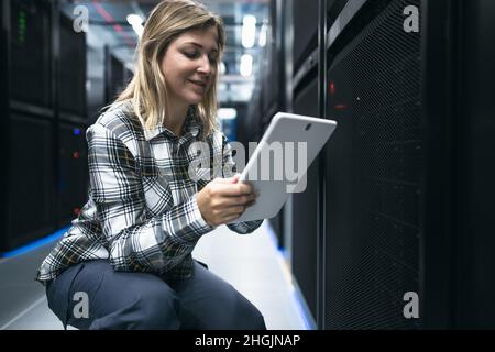 Female data center technician working inside server rack room Stock Photo