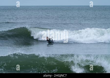 Ocean Wave Trick Roping Bodyboarder performing a 360 trick surfing ocean wave on a cloudy ...