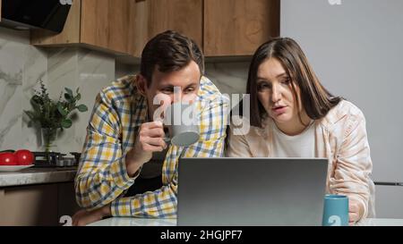 Married couple drink tea and do online shopping in kitchen Stock Photo