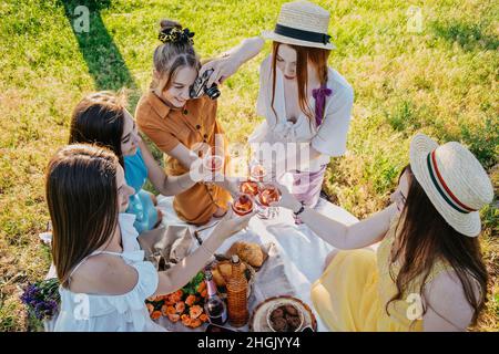 Galentines day. Slumber party. Summer Picnic Party Ideas, Outdoor Gathering with friends. Young women girl friends drinking wine, laughing, having fun Stock Photo