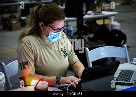 210826-A-YD123-0266 U.S. 5TH FLEET AREA OF OPERATIONS (Aug. 26, 2021) – A U.S. service member processes information on a laptop while assisting U.S. citizens and evacuees arriving from Afghanistan at a location in the U.S. 5th Fleet area of operations prior to onward travel to the United States. The U.S. 5th Fleet region encompasses nearly 2.5 million square miles of water area and is comprised of 20 countries. Stock Photo