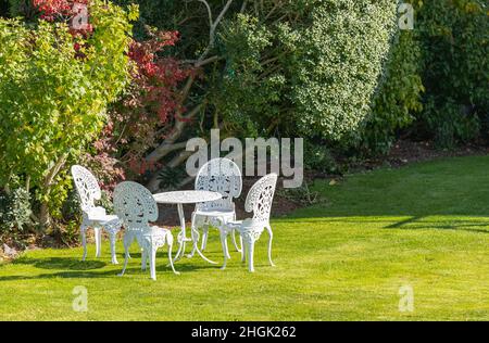 White wrought iron table and chairs vintage style in the garden. Stock Photo