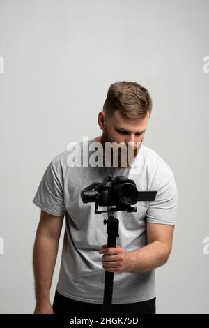 Videographer with a dslr mirrorless camera which set on 3-axis gimbal. Professional video equipment. Portraite of cinematographer. Stock Photo