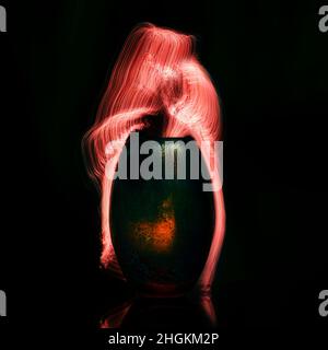 Red fiber optics lights flowing from a glass vase - light painting on black background Stock Photo