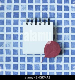 Blank white notepad on blue ceramic mosaic table. top view, copy space Stock Photo