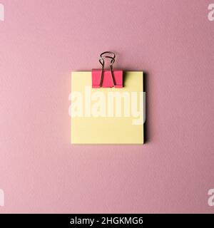 Sticky memo pad and metal clip isolated on pink background. top view, copy space Stock Photo