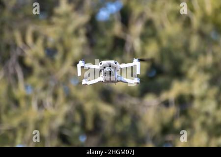 Kharkiv, Ukraine - March 6, 2021: Dji Mavic Mini 2 drone, flying in sunny forest. New quadcopter device hovering with blurry green background Stock Photo