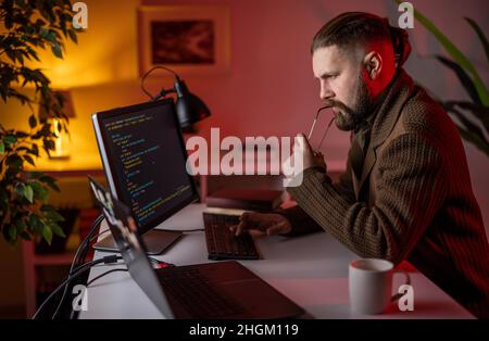 Thoughtful man coding on pc Stock Photo