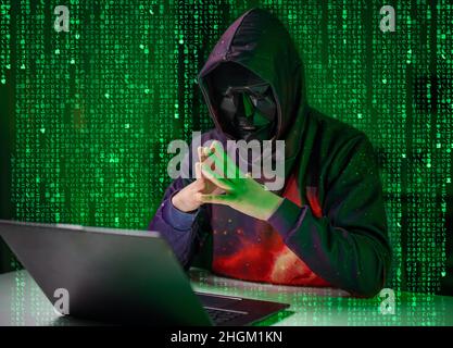 Hacker in mask with laptop Stock Photo