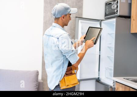 Male worker types on a tablet, kitchen renovation Stock Photo