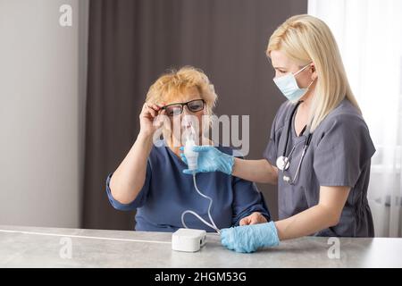 Young Female Doctor Holding Oxygen Mask Over Senior woman Patient's Face. Stock Photo