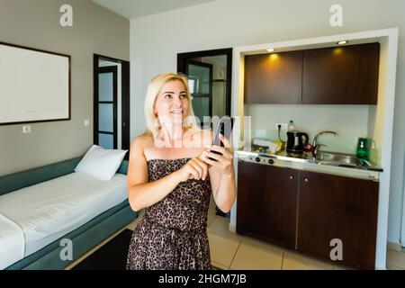 Side view pleasant young woman using smart home system or activating modern alarm system before leaving apartment. Happy lady turning off easy Stock Photo