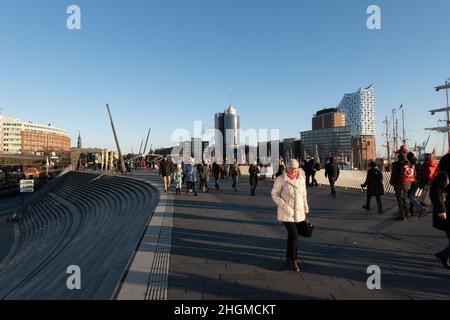 People walking at Hamburg harbour on a sunny day - CITY OF HAMBURG, GERMANY - DECEMBER 21, 2021 Stock Photo