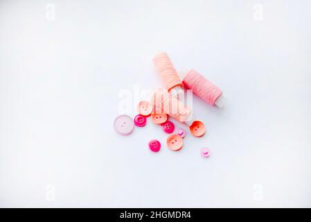 Pink threads and pink buttons on a white background. Sewing themes. Stock Photo
