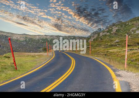 Photograph of a road with yellow line markings winding through the Snowy Mountains in New South Wales in Australia Stock Photo