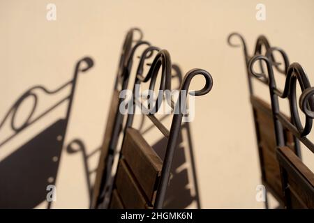 Graphic shadow on the wall from the chairs of a summer cafe on the street. Graceful patterns of reality and shadows on a yellow wall in spring. Riga, Stock Photo