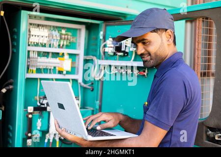 Electrician or repairman using laptop for verifying or inspecting electric distribution board - concpet of maintenance, repair or service man Stock Photo