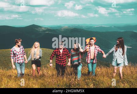 Groups of Friends Relaxing are Enjoying Outside Tents Camping. Group people in a hike through the mountains. Friends on a camping trip walking. Stock Photo