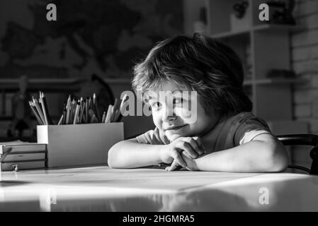 Educational process. Cute pupil with funny face schooling work. Cute little preschool kid boy with teacher study in a classroom. Stock Photo