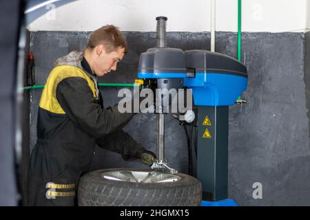 Car master mechanic vulcanizer repairing tire on automatic rubber repair vulcanizer machine in auto vulcanizing and vehicle service workshop Stock Photo